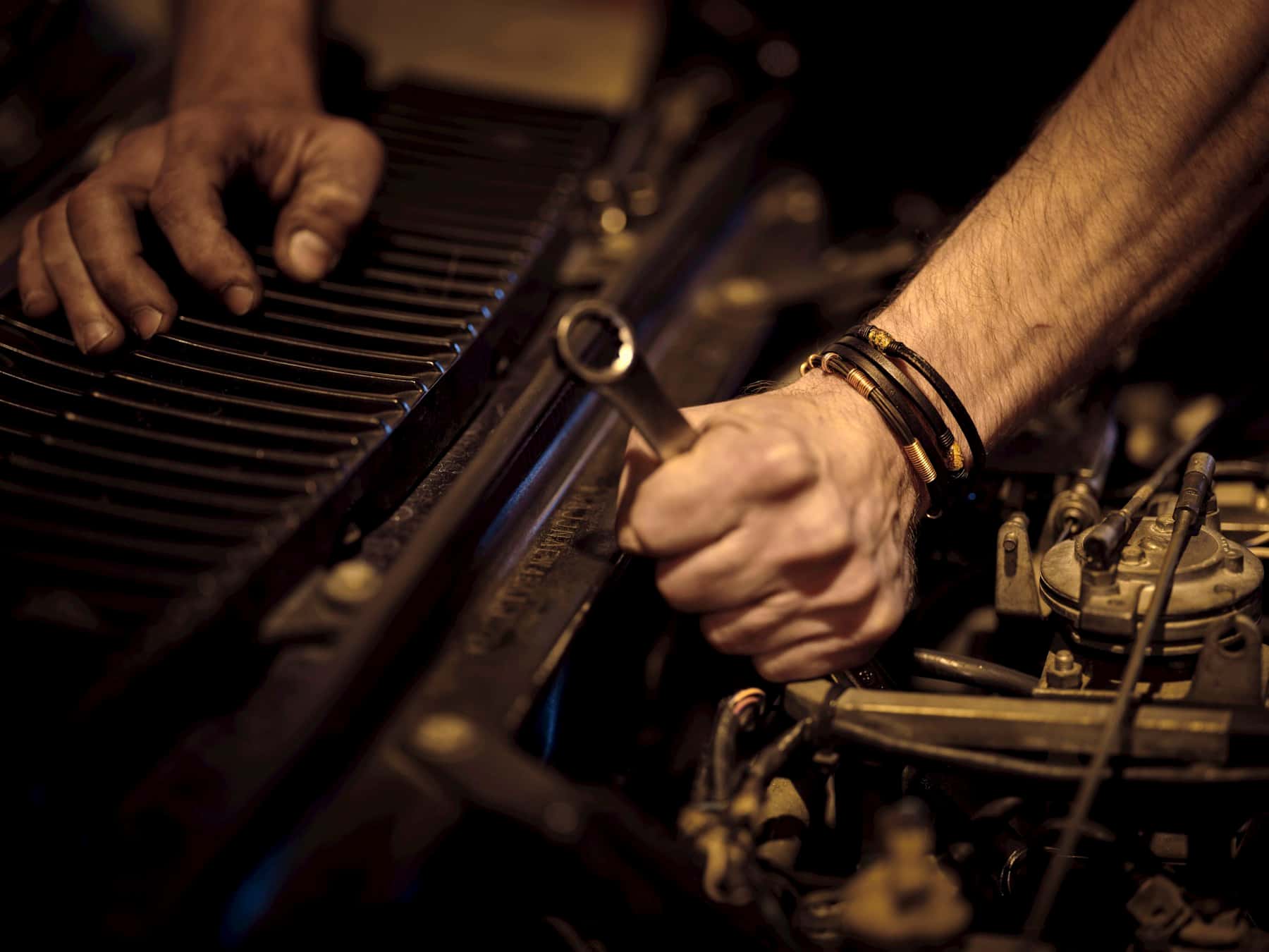 Mechanic's hands working on an engine with a wrench