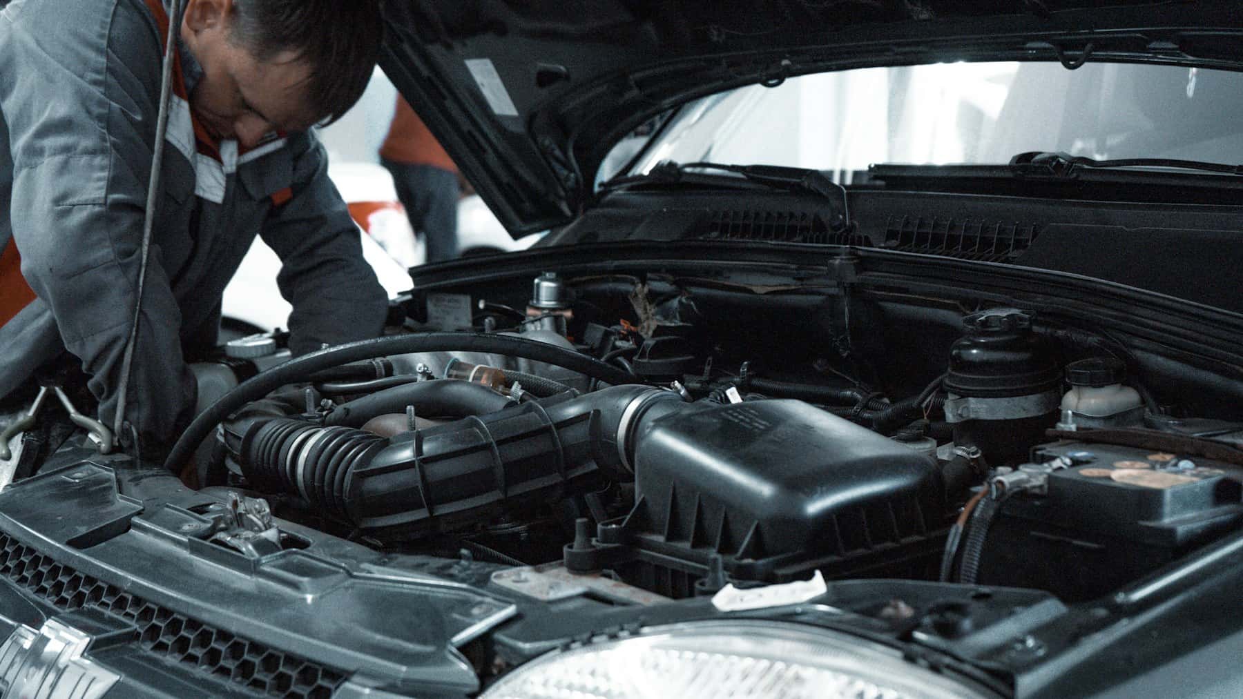 Mechanic in a grey uniform inspecting a car engine