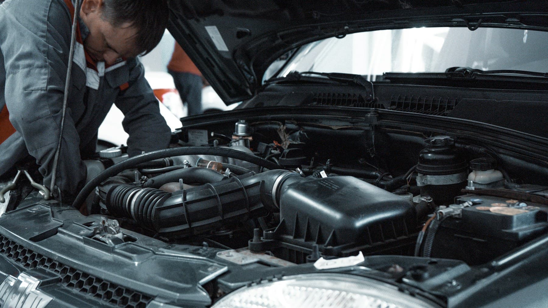 Mechanic in a grey uniform inspecting a car engine